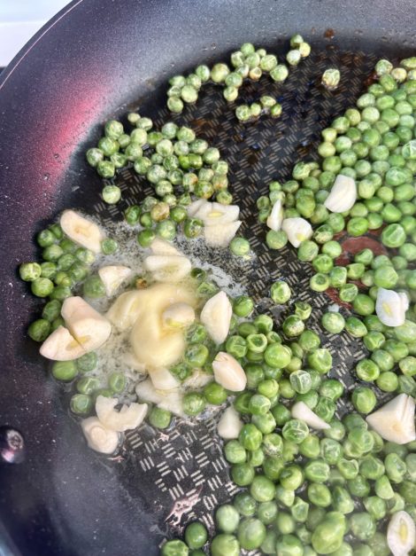 Peas, garlic, and spices cooking in frying pan
