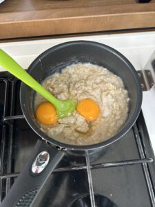 Once the oats have absorbed the water, crack in the two eggs.